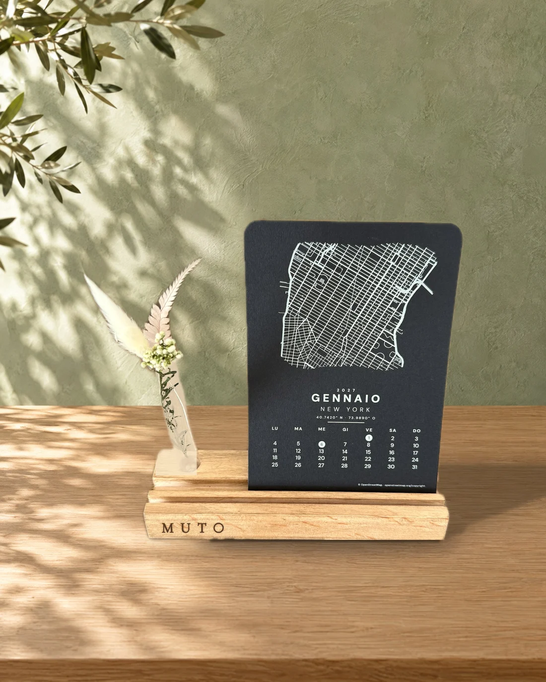 Calendario Linfa: base media con provetta di vetro e fiori secchi, MUTO inciso, cartoncino nero di gennaio con la mappa di New York